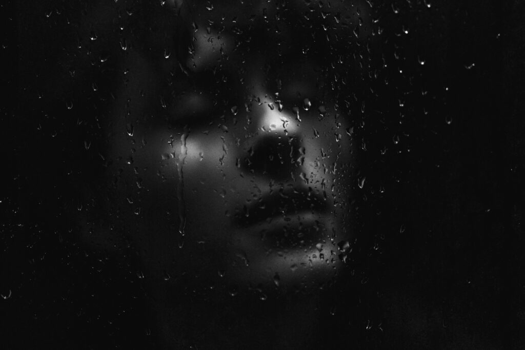 Black and white portrait of a woman with water droplets, evoking a moody and contemplative feel.