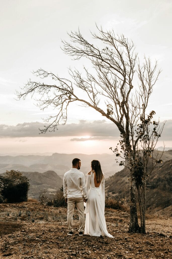 A romantic couple stands lovingly together at sunset with a breathtaking mountain view.